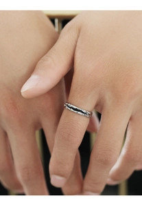 Close-up of vintage silver-toned ring with black stripes and hammered texture on finger