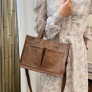 Brown vintage tote bag with dual front pockets shown in a soft lifestyle setting