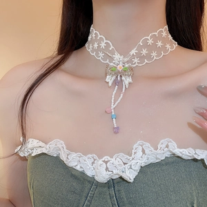 Detail of white lace choker with pink flower and colorful beaded butterfly tassels