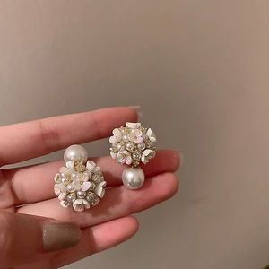 Gros plan de boucles d'oreilles fleurs en perles avec détails de cristaux incrustés