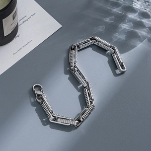 Detail of silver stainless steel chain bracelet with textured links and lobster clasp