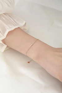 Detalle macro de la pulsera minimalista de plata bañada en oro de 14k con cinco circonitas