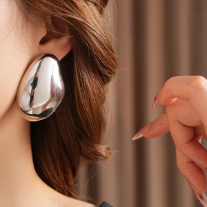 Close-up of high-polish silver teardrop earring on model showing sleek metallic texture