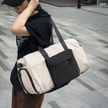 Large beige and black nylon gym bag with shoulder strap shown in a city street setting