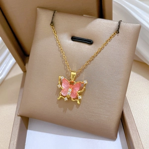 Macro detail of gold butterfly pendant with pink translucent wings and sparkling crystals