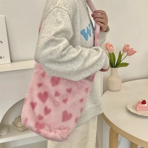 Close-up of pink fuzzy shoulder bag with red heart patterns in a cozy scene