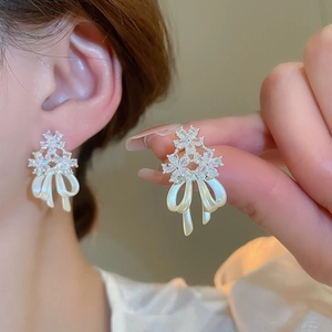 Detail of 14k gold plated flower stud earrings with zircon and pearl bow tassels
