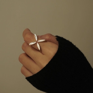Close-up of silver four-pointed star ring worn by a model against black knitwear