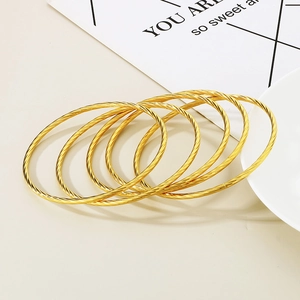 Five-piece set of gold twisted cable titanium steel bracelets for women on warm background
