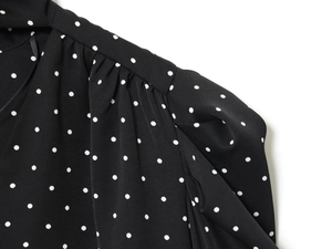 Dettaglio del tessuto a pois e spalla a pieghe su un abito di chiffon nero