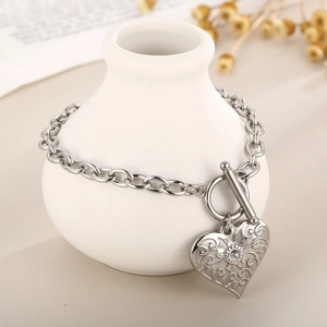 Vintage silver OT buckle bracelet with hollow heart pendant on a decorative vase