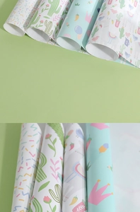 Close-up of wrapping paper rolls with cute unicorn, alpaca and cactus cartoon patterns
