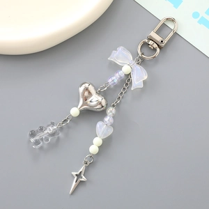 Iridescent mermaid bow and bear keychain with silver charms on a light background