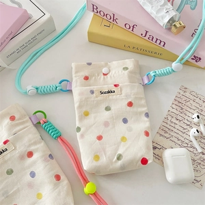 Close-up of beige canvas pouch with colorful polka dots and thick woven shoulder straps