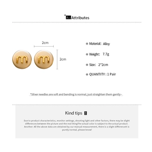 Detail specifications of beige round stud earrings with golden letter m and silver pins