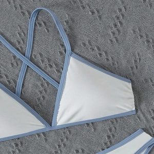 Detail of white and blue bikini top with crisscross straps and precise stitching finish