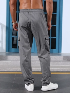Detail view of men's grey cargo pants featuring a drawstring waist and rear flap pockets