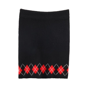 Detailed view of women's knitted skirt with classic red and white argyle pattern on black