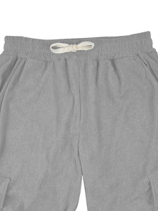 Detail view of grey corduroy pants featuring a white cotton drawstring and elastic waistband