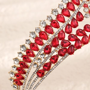 Close-up of luxury gold bridal crown with red pear-cut stones and sparkling rhinestones