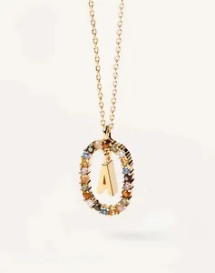 Macro view of gold necklace with oval pendant featuring colorful gemstones and letter A