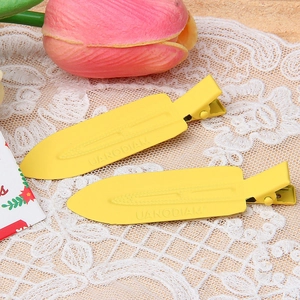 Macro detail of yellow matte finish metal duckbill clips on a delicate lace background