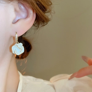 Elegant gold-plated flower earrings with white zircon drop shown on a female model