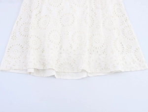 Detailed view of white eyelet lace embroidery and delicate hollow-out pattern on dress hem