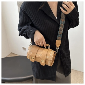 Brown vintage cylinder crossbody bag with ethnic patterned wide fabric shoulder strap on model