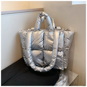 Detail of silver quilted tote bag showing high-gloss metallic finish and soft padded texture