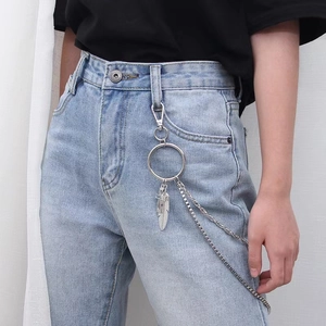 Detail view of multi-layer silver waist chain with feather pendant on blue denim jeans