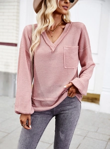 Detail of pink waffle knit V-neck top featuring a front pocket and soft texture