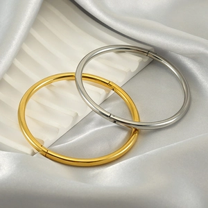 Close-up of gold and silver minimalist bangles featuring a side hinge opening mechanism