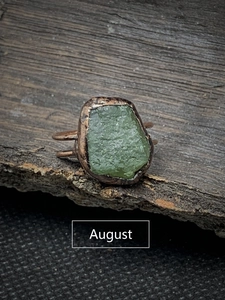 Macro shot of an irregular green peridot raw stone on a bronze vintage style ring band