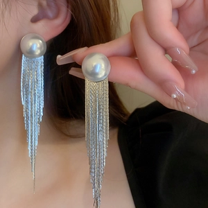 Elegant pearl and metallic tassel drop earrings worn by a model for a chic style