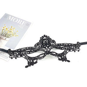 Close-up of black lace masquerade mask with intricate patterns and ties on white surface