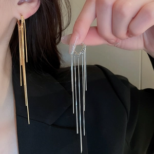 Macro shot of gold and silver plated long tassel earrings on model with high gloss finish