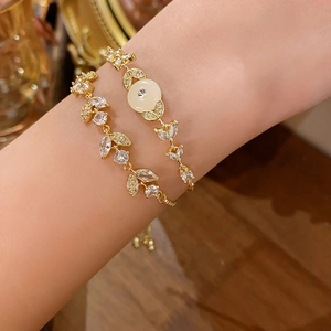 Dettaglio di bracciali placcati in oro con zirconi e pietra occhio di gatto al polso
