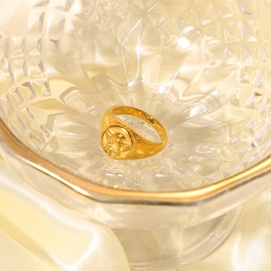 French vintage gold angel embossed ring displayed on champagne silk and elegant glass
