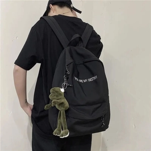 Vue détaillée d'un sac à dos d'étudiant noir avec un pendentif grenouille en peluche