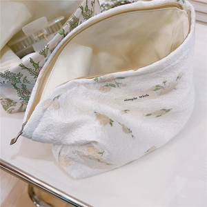 Detail of floral makeup bag featuring simple wish woven label and zipper closure
