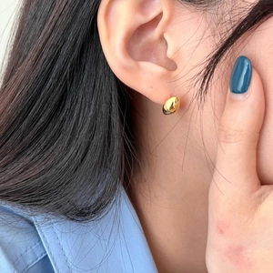 Minimalist gold S925 sterling silver bean stud earring worn on a model's ear