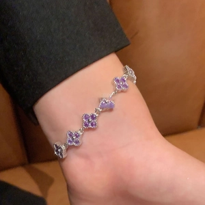Detail of silver clover chain bracelet with purple zircon inlay worn on wrist