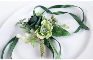 Detail of a dark green PE rose wrist corsage with berries and satin ribbons on a white plate