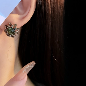 Macro view of vintage French style green flower stud earring with rhinestones on ear