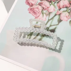 Detail of holographic rectangular pearl hair claw clip with golden spring on floral page