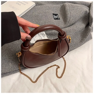 Detailed interior view of a brown leather half-moon bag showing zip pocket and chain strap