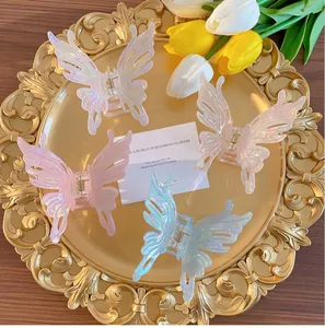 Detail of four colorful acrylic butterfly hair claws displayed on a decorative gold tray