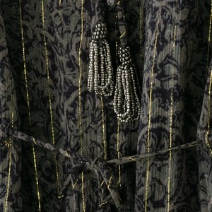 Détail de la robe en ramie bohème avec rayures dorées, imprimé vintage et glands perlés