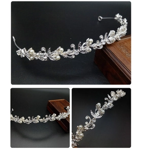 Detail view of silver tiara crown with pearls and rhinestones on a dark background